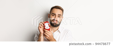 Close-up of hopeful man begging to marry him, looking sad and showing wedding ring, making a proposal, white background Close-up of hopeful man begging to marry him, looking sad and showing wedding ring, making a proposal, white background 94478677