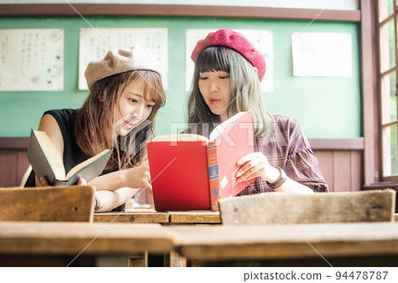 Two women looking at a book and having fun 94478787