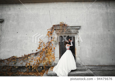 Beautiful bride and groom embracing and kissing on their wedding day outdoors 94479876