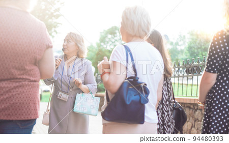female guide is telling a group of tourists about something. 94480393