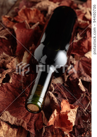 Red wine on dried-up vine leaves. 94480786