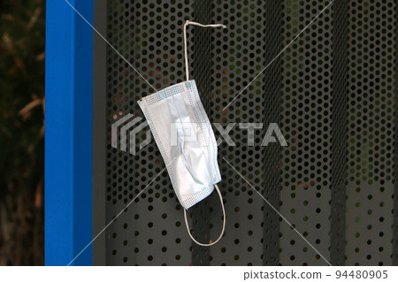 An old medical mask from covid 19 (COVID-19) is lying on the stre An old medical mask from covid 19 (COVID-19) is lying on the stre 94480905