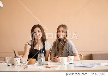 Front view of four beautiful caucasian female at art workshop. A young teacher teaches drawing Front view of four beautiful caucasian female at art workshop. A young teacher teaches drawing 94481488