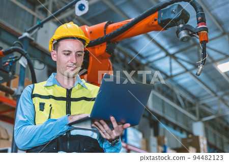 Caucasian engineer male worker working in metal factory with robot welding machine programmer controller and monitor. Caucasian engineer male worker working in metal factory with robot welding machine programmer controller and monitor. 94482123