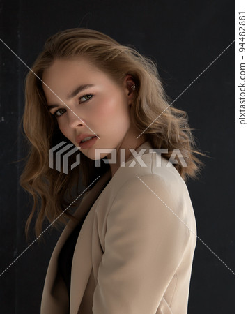 A fashionable diva in a beige jacket on a gray 94482881