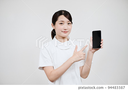 A woman in a white coat operating a smartphone A woman in a white coat operating a smartphone 94483387