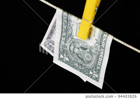 One dollar fastened with a clothespin is dried on a clothesline on a dark background 94483826