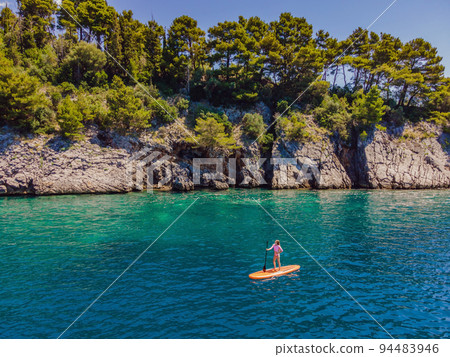 Young women Having Fun Stand Up Paddling in blue water sea in Montenegro. SUP. girl Training on Paddle Board near the rocks Portrait of a disgruntled girl sitting at a cafe table 94483946