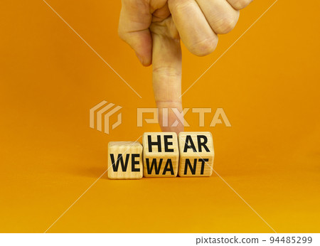 We hear and want symbol. Concept words We hear we want on wooden cubes. Businessman hand. Beautiful orange table orange background. Business and we hear and want concept. Copy space. 94485299