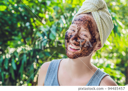 Face Skin Scrub. Portrait Of Sexy Smiling Female Model Applying Natural Coffee Mask, Face Scrub On Facial Skin. Closeup Of Beautiful Happy Woman With Face Covered With Beauty Product. High Resolution 94485457