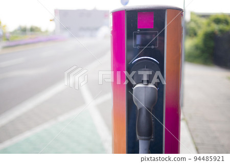 Electric car charging station for charge EV battery. Plug for vehicle with electric engine. EV charger. Clean energy. Charging point at car parking lot. Future transport technology. 94485921