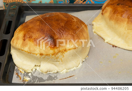 Handmade home stile delicious pies with different fillings cooked in the dark warm oven are preparing on the cooking paper at kitchen using special form inside the hot oven. Close-up picture. 94486205