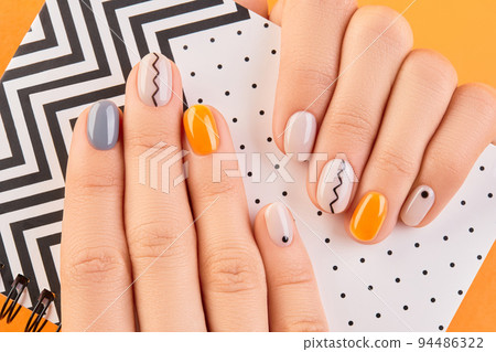 Close up womans hands with trendy minimal manicure on orange background. Autumn nail design Close up womans hands with trendy minimal manicure on orange background. Autumn nail design 94486322