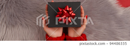 Manicured womans hands holding gift box on furry background Manicured womans hands holding gift box on furry background 94486335