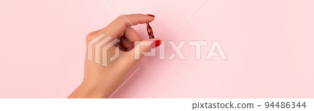 Manicured female hand with tiny bottle of soft drink on pink background 94486344