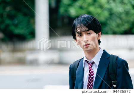 Male high school student walking on the sidewalk 94486872