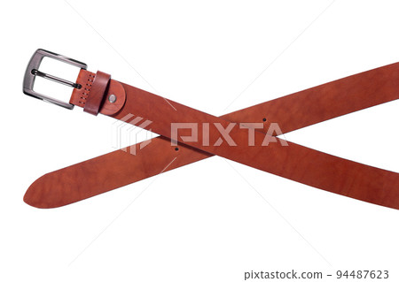 A crossed brown leather belt with a metal buckle on a white background is isolated. A crossed brown leather belt with a metal buckle on a white background is isolated. 94487623