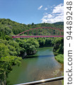 red iron bridge over river 94489248