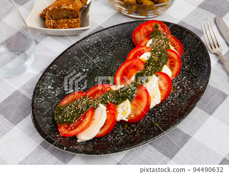 Caprese salad with fresh tomatoes and mozzarella dressed with pesto Caprese salad with fresh tomatoes and mozzarella dressed with pesto 94490632