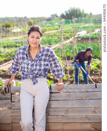 Female gardener posing with a shovel in garden Female gardener posing with a shovel in garden 94490670