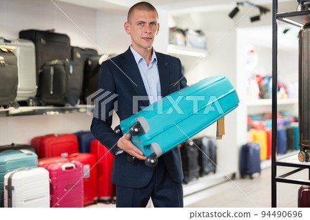 Portrait of a contented man holding a travel suitcase Portrait of a contented man holding a travel suitcase 94490696