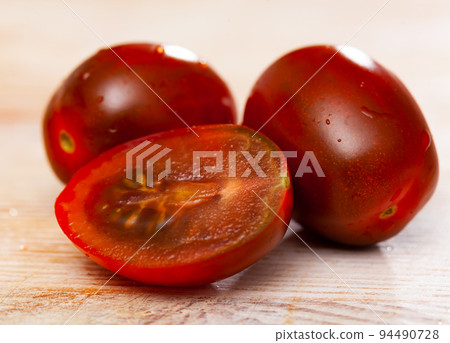 Closeup of fresh cherry kumato tomatoes with chopped slices 94490728