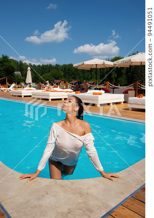 Sensual lady in wet dress standing in pool on sunny summer day 94491051