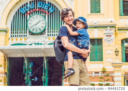 Father and son on background Saigon Central Post Office on blue sky background in Ho Chi Minh, Vietnam. The inscription on the Vietnamese post office Father and son on background Saigon Central Post Office on blue sky background in Ho Chi Minh, Vietnam. The inscription on the Vietnamese post office 94491720