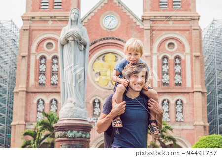 Father and son in the background Notre dame de Saigon Cathedral, build in 1883 in Ho Chi Minh city, Vietnam 94491737