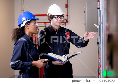 Electrical young woman and man engineer examining maintenance cabinet system electric. Electrical young woman and man engineer examining maintenance cabinet system electric. 94493028