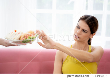 Hands serving food and young caucasian woman making sign say no food unhealthy with obese. Hands serving food and young caucasian woman making sign say no food unhealthy with obese. 94493098