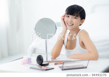Beautiful face of young asian woman with happy smiling and touch cheek looking mirror. 94493270