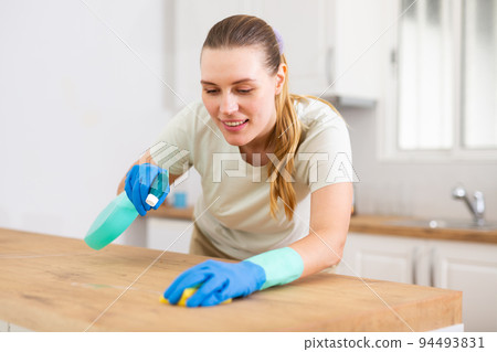 pretty woman is cleaning with detergent in kitchen pretty woman is cleaning with detergent in kitchen 94493831
