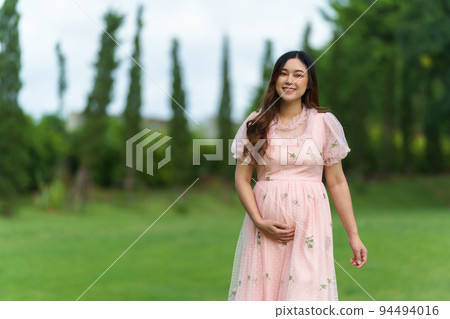 happy pregnant woman walking in park 94494016