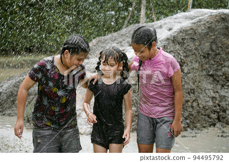 Group of happy children girl playing in wet mud puddle during raining in rainy season 94495792