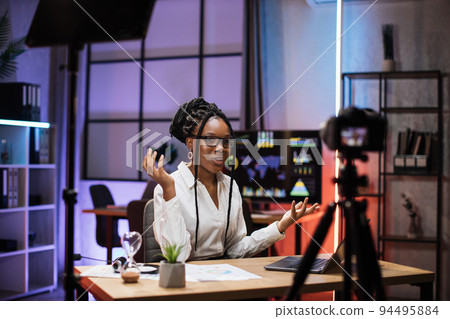 Confident african american businesswoman, broker in white shirt sitting in front of camera Confident african american businesswoman, broker in white shirt sitting in front of camera 94495884