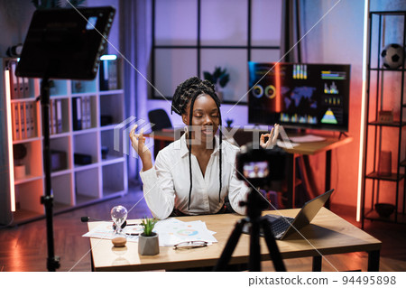 Relaxed african businesswoman in formal wear meditating with closed eyes and mudra hands 94495898