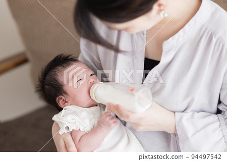 Family Baby drinking milk from a baby bottle Family Baby drinking milk from a baby bottle 94497542