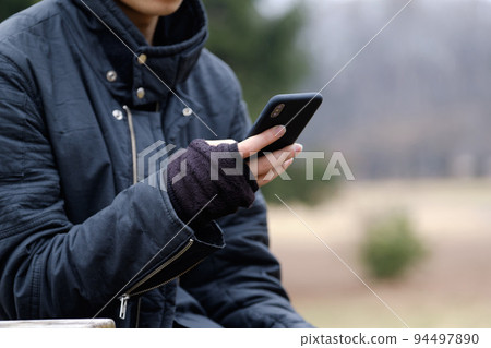 冬天在戶外用無指手套操作智能手機的男人 94497890