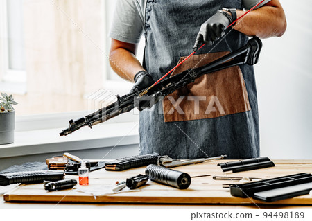 Close up of a gunsmith cleaning firearm barrel with ramrod brush 94498189