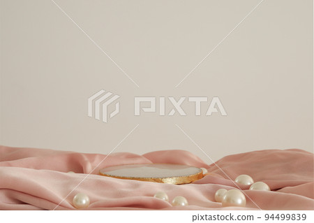 White marble podium with gold on the pink silk fabric with pearls, white background. Podium for product, cosmetic presentation. Creative mock up. Pedestal or platform for beauty products. 94499839
