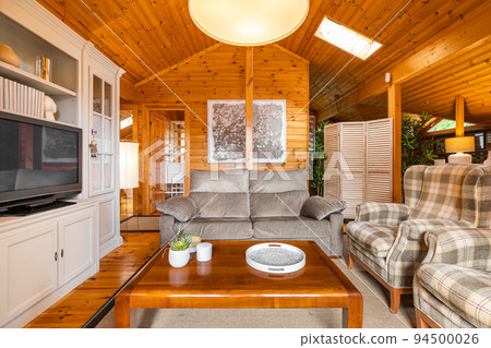 Beautiful interior of cozy living room with sofa and armchairs in a wooden house. Life in a village Beautiful interior of cozy living room with sofa and armchairs in a wooden house. Life in a village 94500026