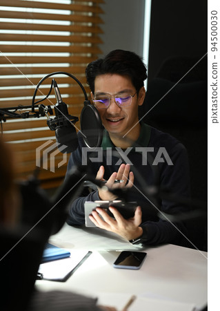 Young podcaster using a microphone and laptop computer recording audio for channel in home studio Young podcaster using a microphone and laptop computer recording audio for channel in home studio 94500030