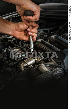 Auto mechanic working on car engine in mechanics garage. Repair service. Close-up shot. Free space for text, copy space 94500270
