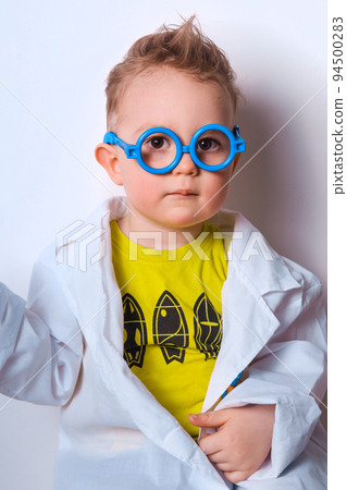 Little explorer. Boy plays scientist. Funny child with blue glasses. Cute, colorful photo. Kid portrait in doctor or science costume. 94500283