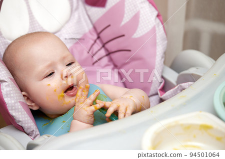 baby girl eating with spoon in kitchen baby girl eating with spoon in kitchen 94501064
