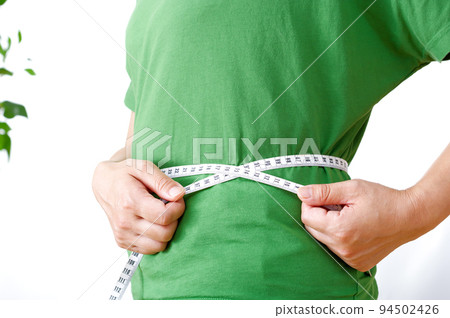 Woman putting a tape measure on her waist 94502426