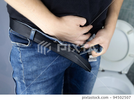 Prostatitis concept. Rear view of a man, hard to pee. Difficulty urinating with prostatitis. View of the toilet and the legs of a man. Imitation of urine with clear water. Sick in the toilet 94502507