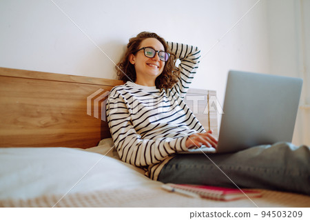 Young female freelancer works and makes notes while working at home in quarantine lockdown. Freelancer. Young female freelancer works and makes notes while working at home in quarantine lockdown. Freelancer. 94503209
