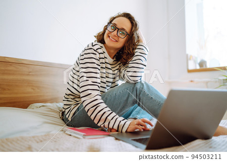Young female freelancer works and makes notes while working at home in quarantine lockdown. Freelancer. 94503211